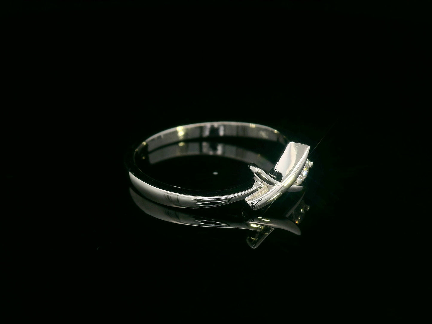 18K white gold ring featuring a 0.12 ct round diamond in a modern tension “X” design, with certificate of authenticity.