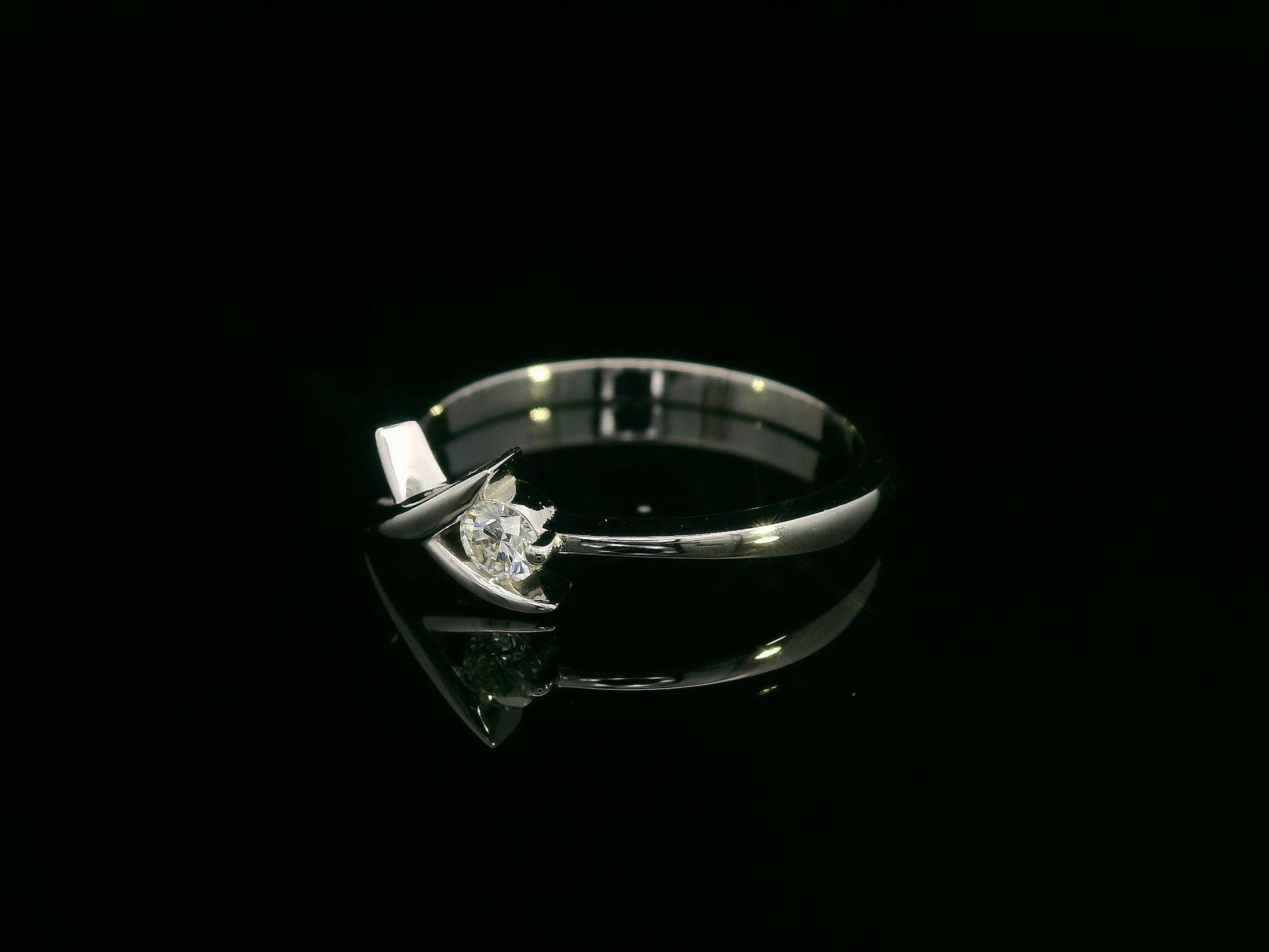 18K white gold ring featuring a 0.12 ct round diamond in a modern tension “X” design, with certificate of authenticity.