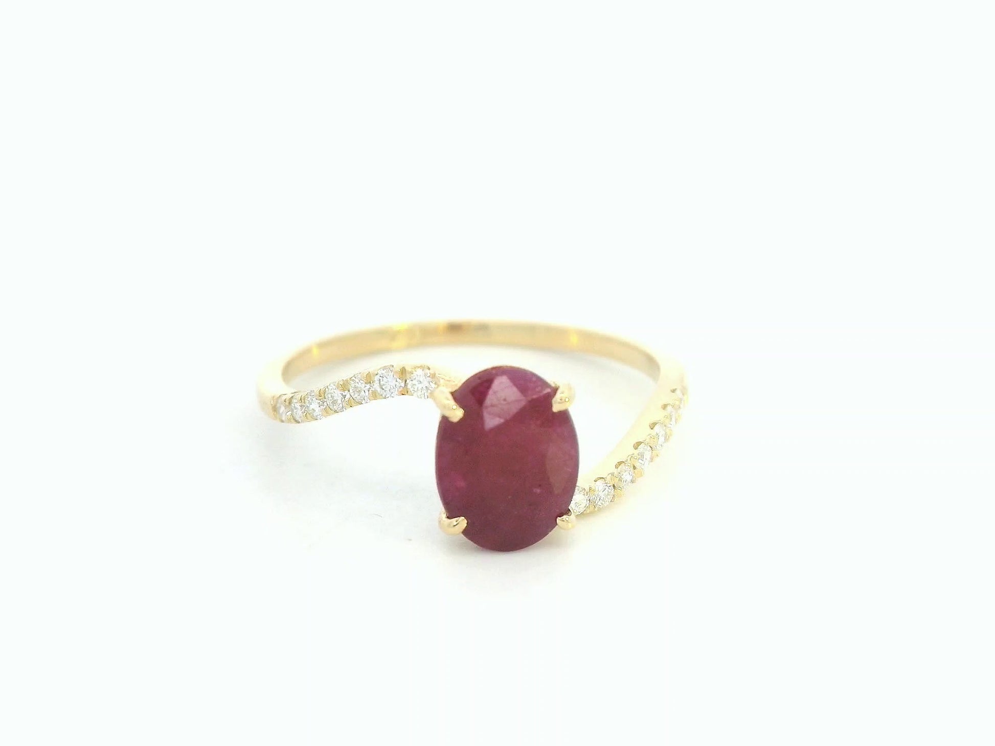 18K yellow gold ruby and diamond wave ring featuring an oval 1.56ct ruby and 0.13ct round diamonds in a flowing wave design.