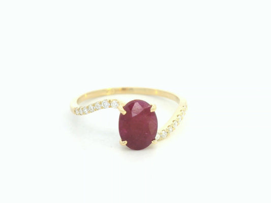 18K yellow gold ruby and diamond wave ring featuring an oval 1.56ct ruby and 0.13ct round diamonds in a flowing wave design.