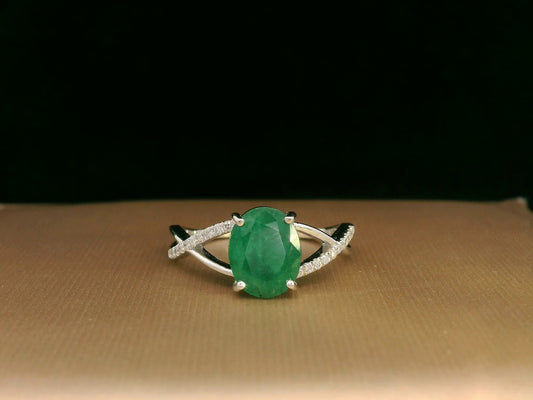 18K white gold ring featuring a 1.59ct oval-cut emerald with 0.10ct diamonds set into a twisted split-shank design.