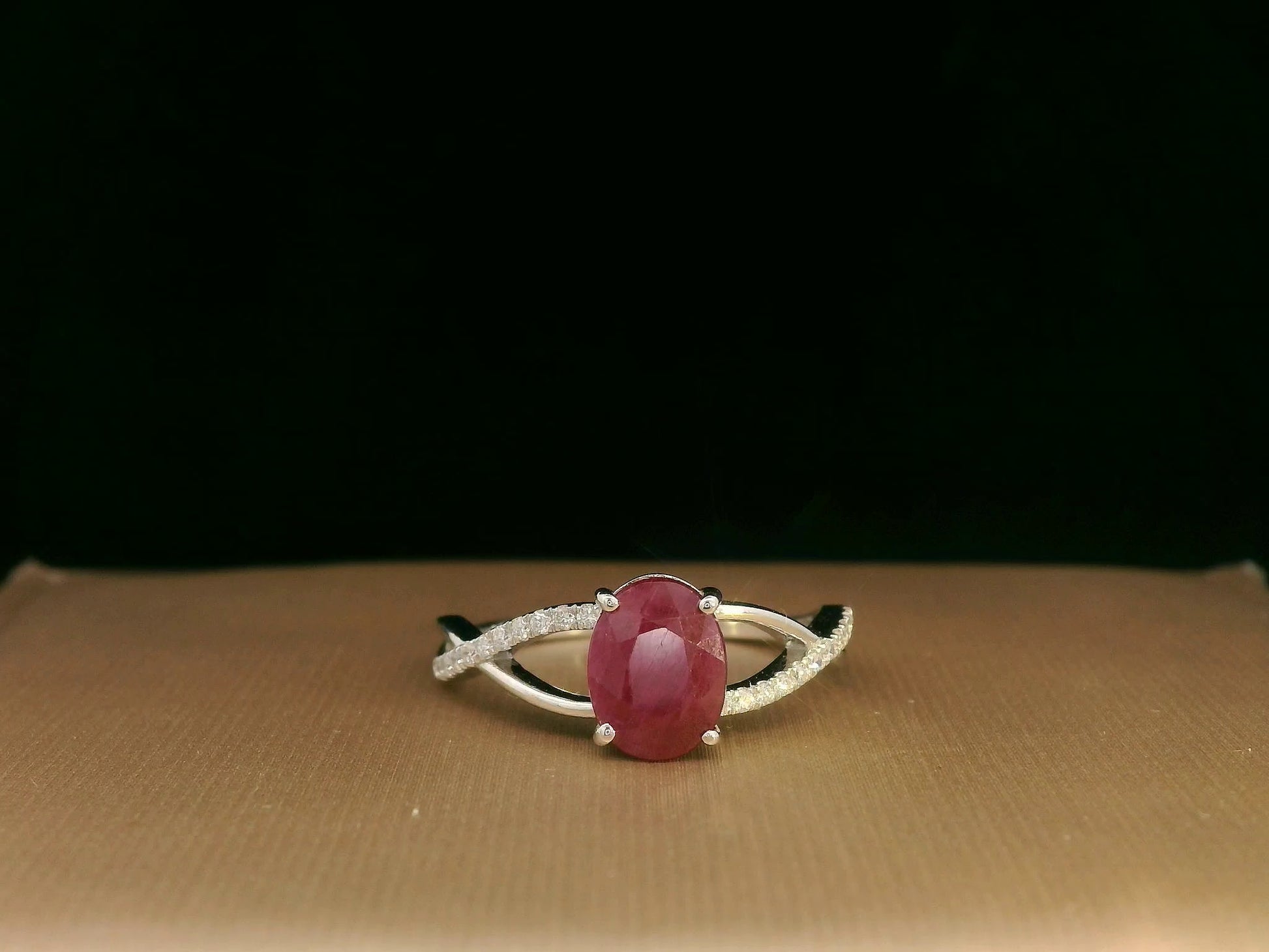 18K white gold ring featuring a 1.47ct oval-cut ruby with 0.11ct diamonds set along a twisted split-shank band.