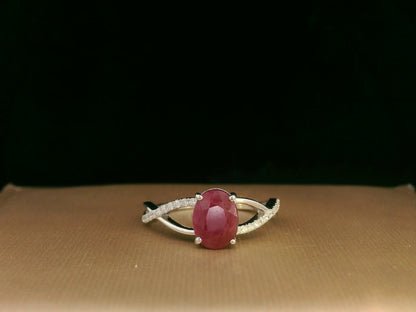 18K white gold ring featuring a 1.47ct oval-cut ruby with 0.11ct diamonds set along a twisted split-shank band.