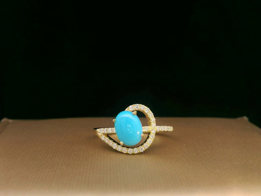 18K yellow gold ring featuring a 1.21ct oval turquoise center with 0.24ct diamonds in an asymmetrical halo and diamond-lined shank.