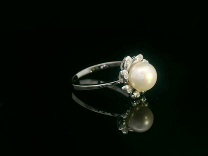 18K white gold ring featuring a luminous freshwater pearl at the center, surrounded by a floral-inspired setting with 0.06ct round diamonds.