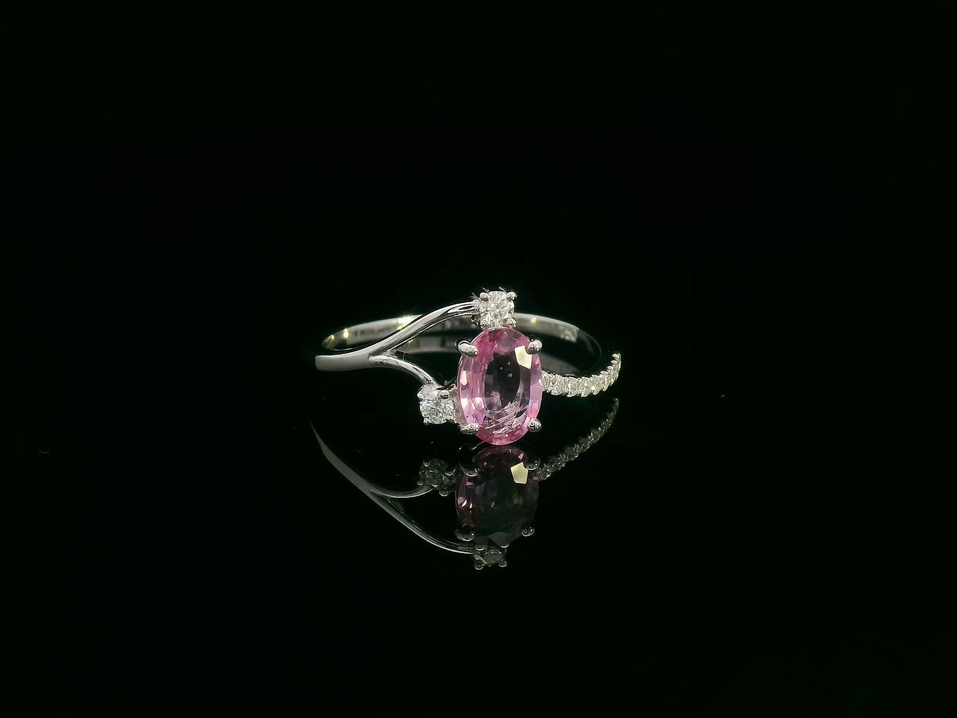 18K white gold ring featuring a 0.75ct oval Pink Sapphire with 0.12ct diamonds on an asymmetric split band.