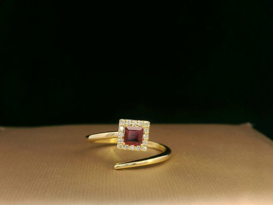 18K yellow gold ring featuring a 0.36ct square-cut ruby with 0.08ct diamonds in a halo setting on a contemporary open-bypass band.