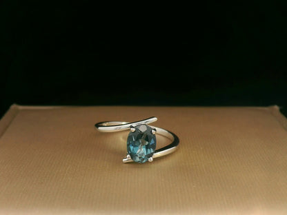 18K white gold bypass ring featuring a 1.49ct oval London Blue Topaz prong-set between gracefully crossing bands.