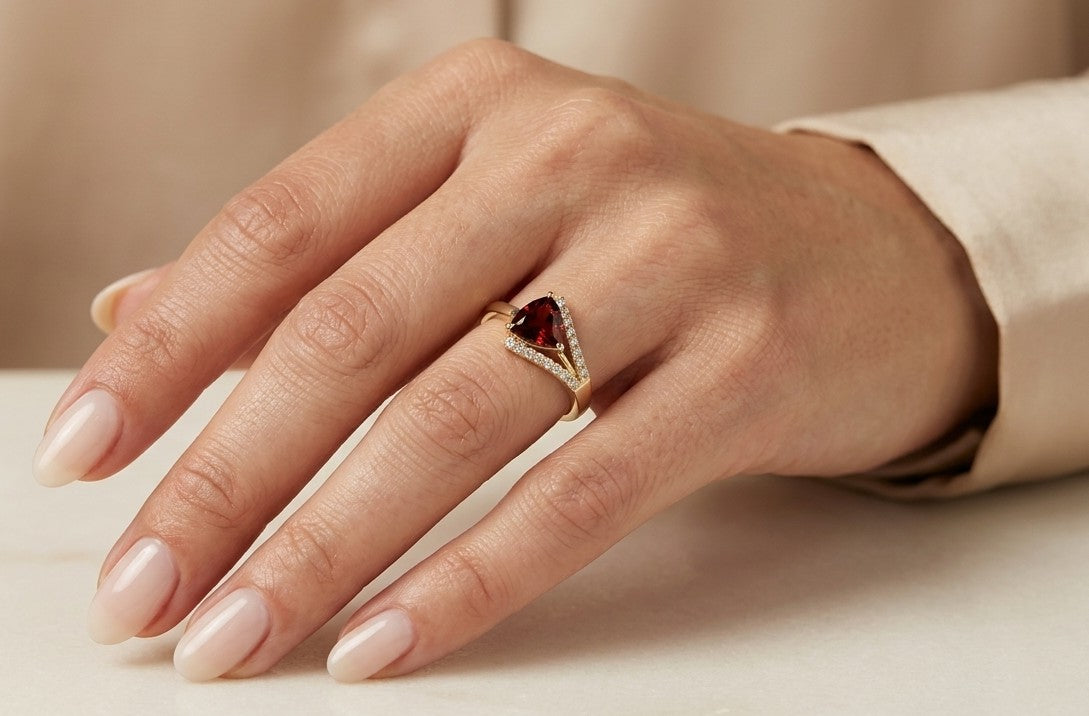 18K yellow gold ring featuring a 1.18 carat trillion-cut red garnet framed by sweeping round diamond accents
