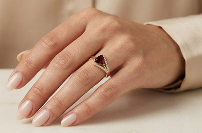 18K yellow gold ring featuring a 1.18 carat trillion-cut red garnet framed by sweeping round diamond accents
