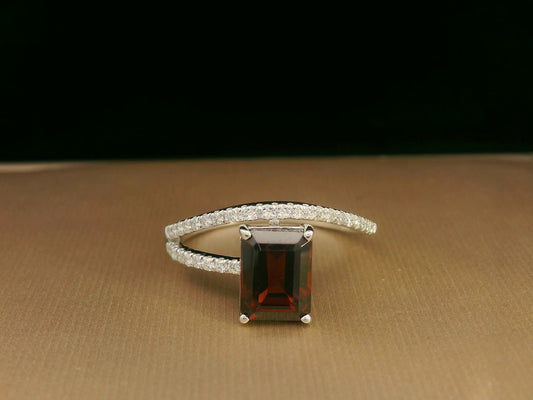 18K white gold bypass ring with emerald-cut garnet and diamond accents