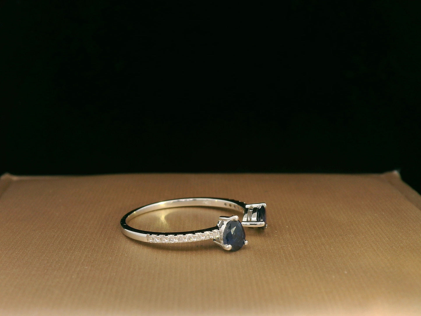 18K white gold open cuff ring with two teardrop-cut blue sapphires (0.70 carat) and 0.10 carat diamond pavé, modern minimalist design