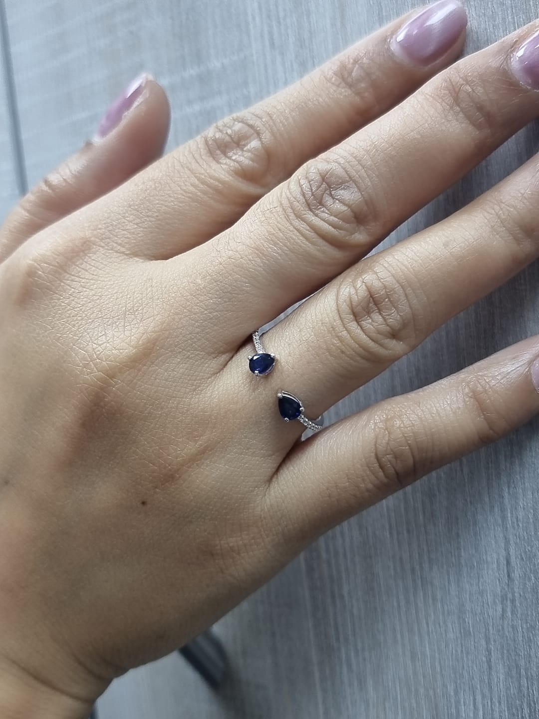 18K white gold open cuff ring with two teardrop-cut blue sapphires (0.70 carat) and 0.10 carat diamond pavé, modern minimalist design