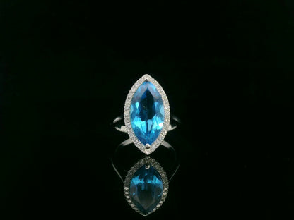 Marquise-cut blue topaz ring with diamond halo in 18K gold. 