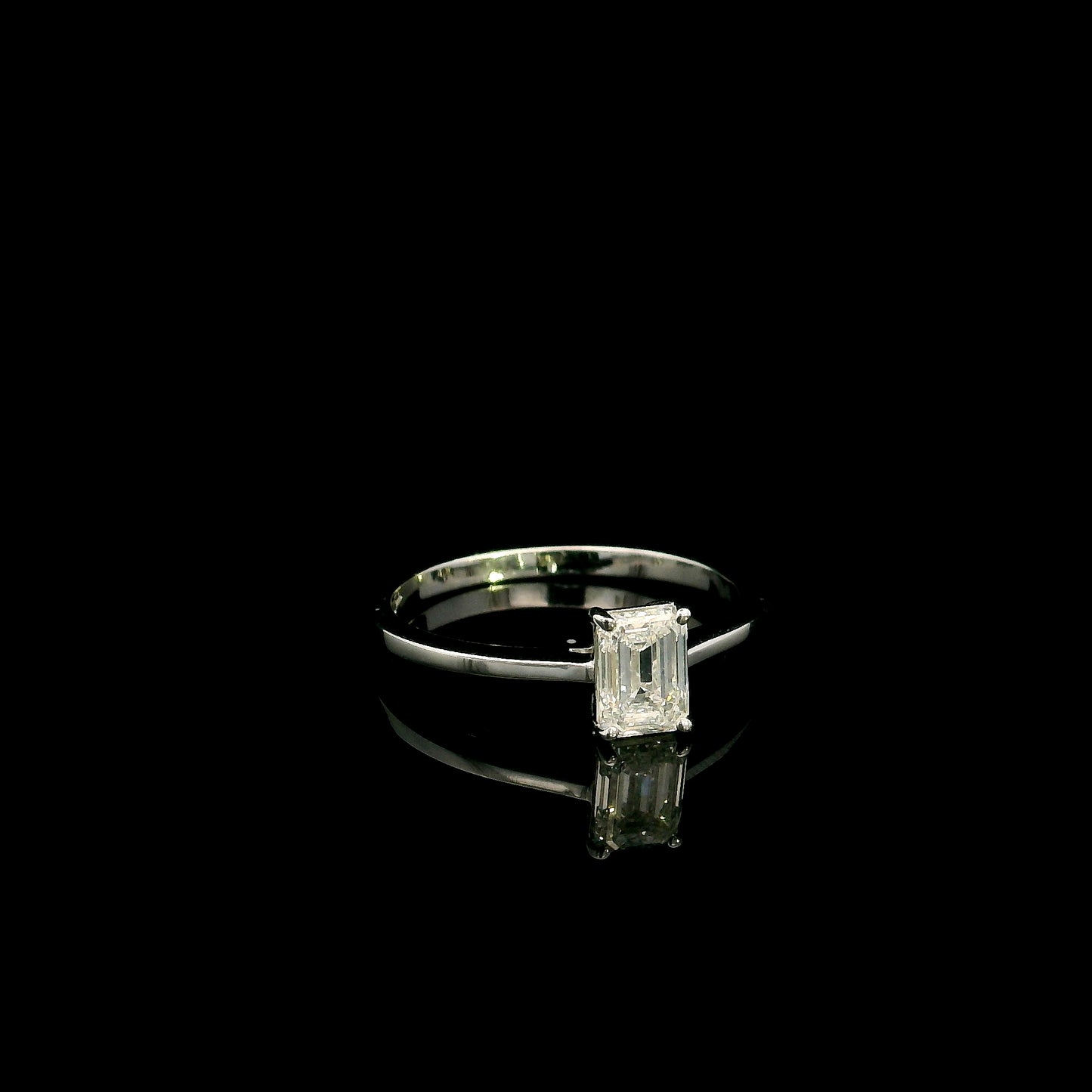 18K white gold solitaire ring featuring a 0.90 carat IGI certified natural emerald cut diamond with VS2 clarity and D colour in a classic four-prong setting.