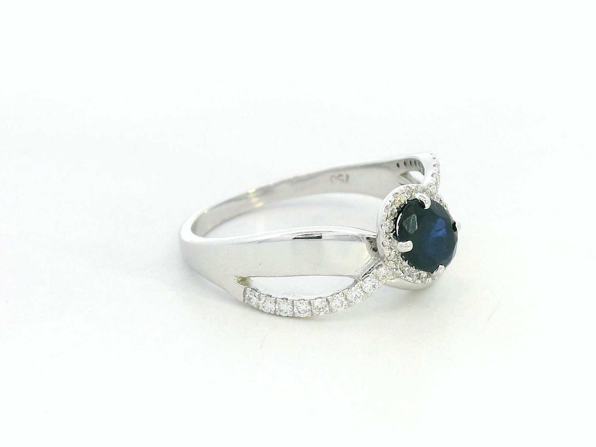 18K white gold blue sapphire and diamond bypass ring with oval sapphire and halo, 0.77 carat sapphire and 0.25 carat total diamond weight, fine jewelry by Emirates Diamonds