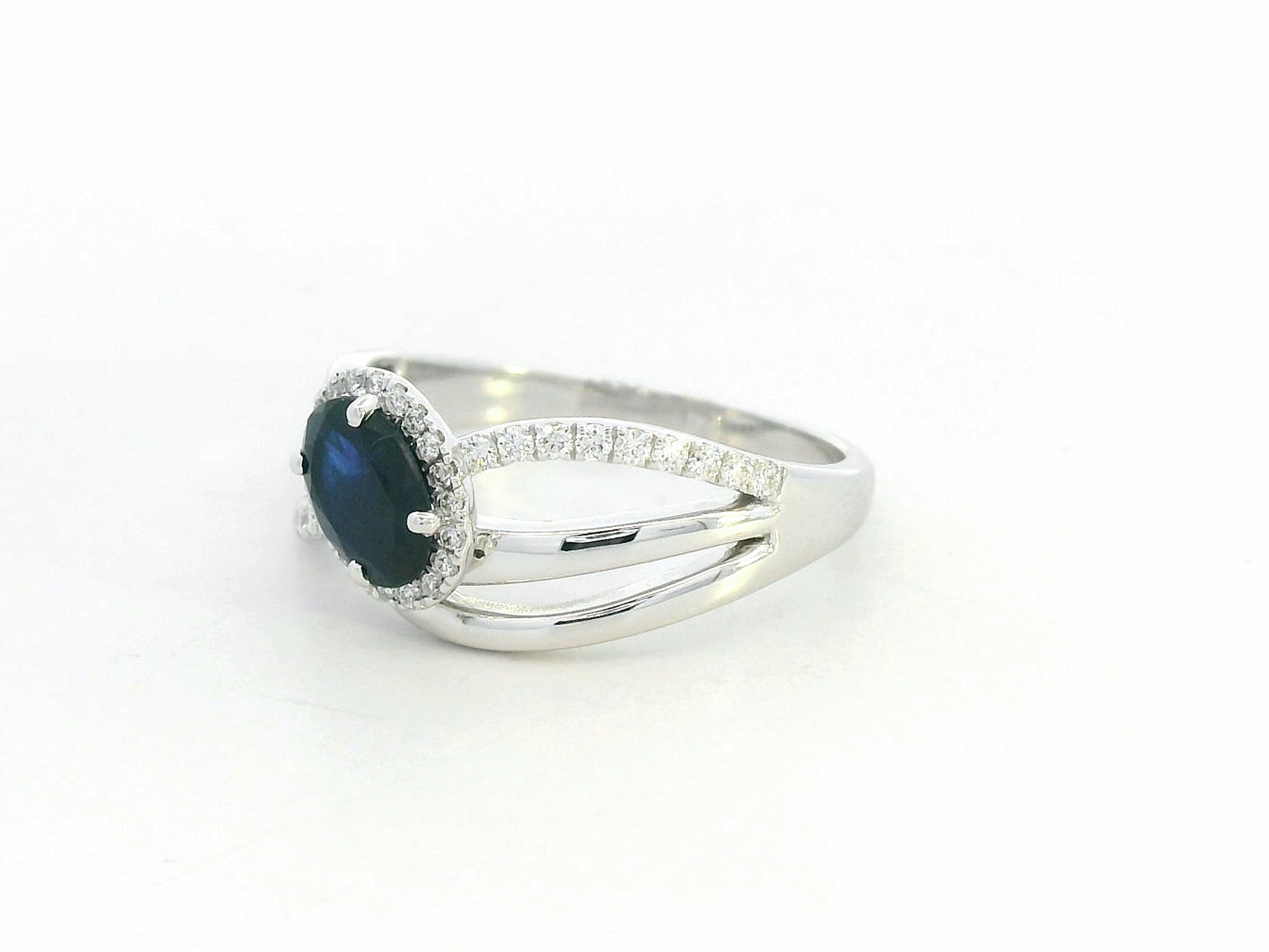 18K white gold blue sapphire and diamond bypass ring with oval sapphire and halo, 0.77 carat sapphire and 0.25 carat total diamond weight, fine jewelry by Emirates Diamonds