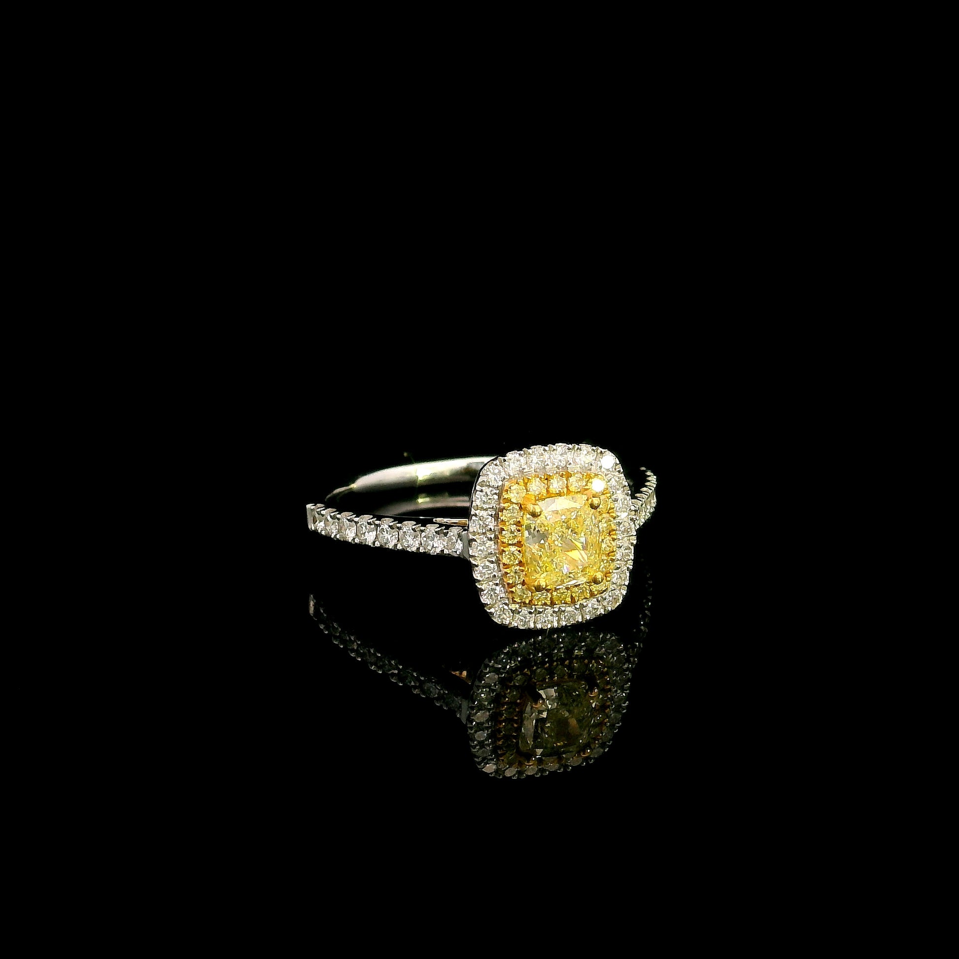 18K white gold engagement ring featuring a 0.58 carat GIA certified Fancy Yellow cushion cut diamond with SI1 clarity, surrounded by yellow and white diamond double halos with a diamond-set band.
