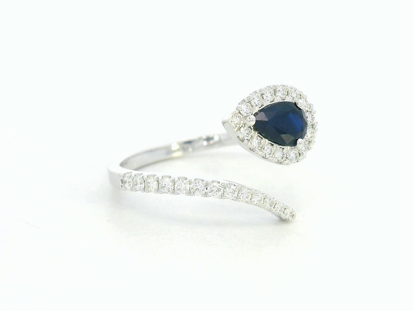 18K white gold bypass ring with pear-shaped blue sapphire and diamond halo by Emirates Diamonds