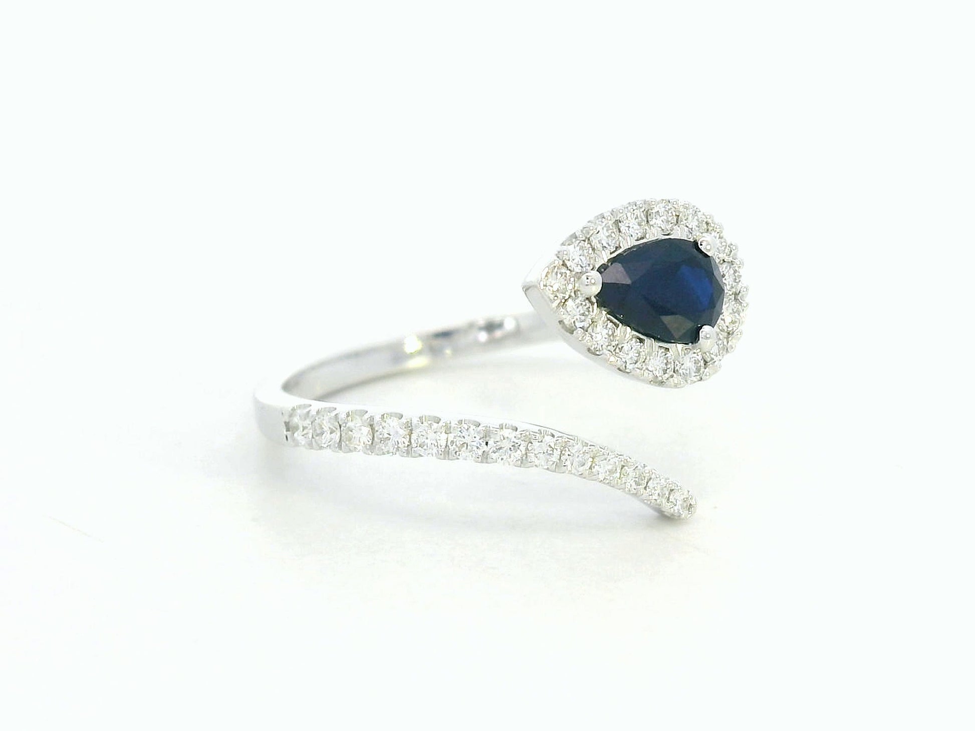 18K white gold bypass ring with pear-shaped blue sapphire and diamond halo by Emirates Diamonds
