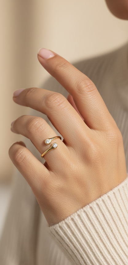 18K yellow gold diamond bypass ring with two round bezel-set diamonds, modern open design by Emirates Diamonds