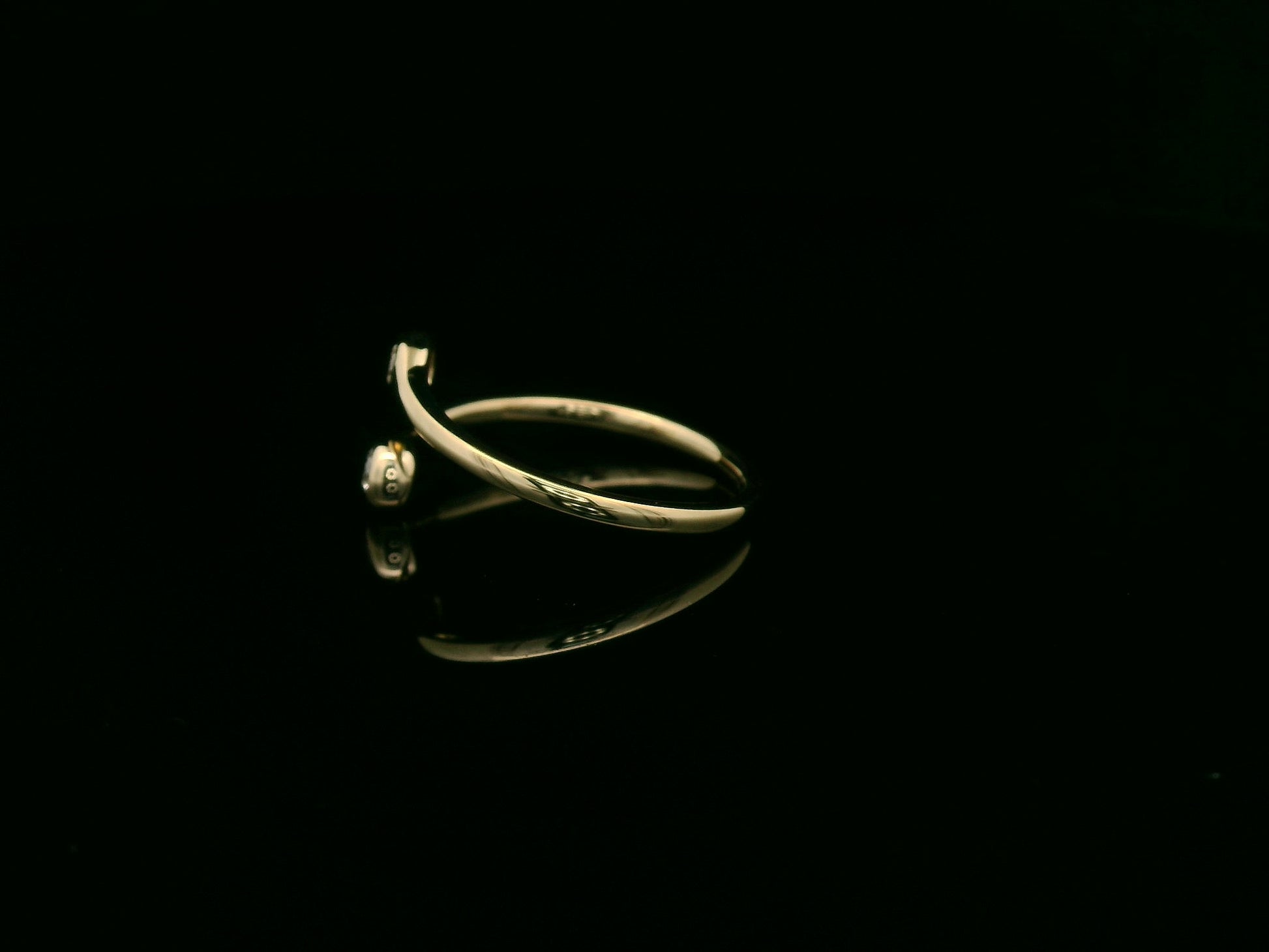 18K yellow gold diamond bypass ring with two round bezel-set diamonds, modern open design by Emirates Diamonds