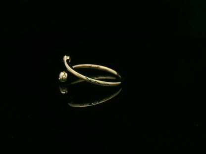 18K yellow gold diamond bypass ring with two round bezel-set diamonds, modern open design by Emirates Diamonds