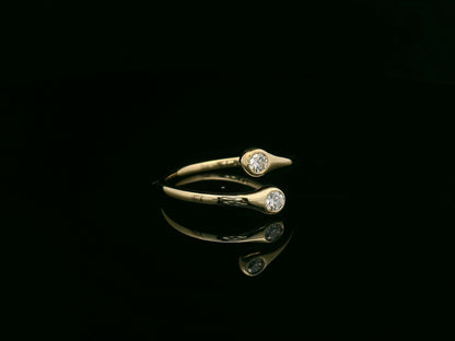 18K yellow gold diamond bypass ring with two round bezel-set diamonds, modern open design by Emirates Diamonds