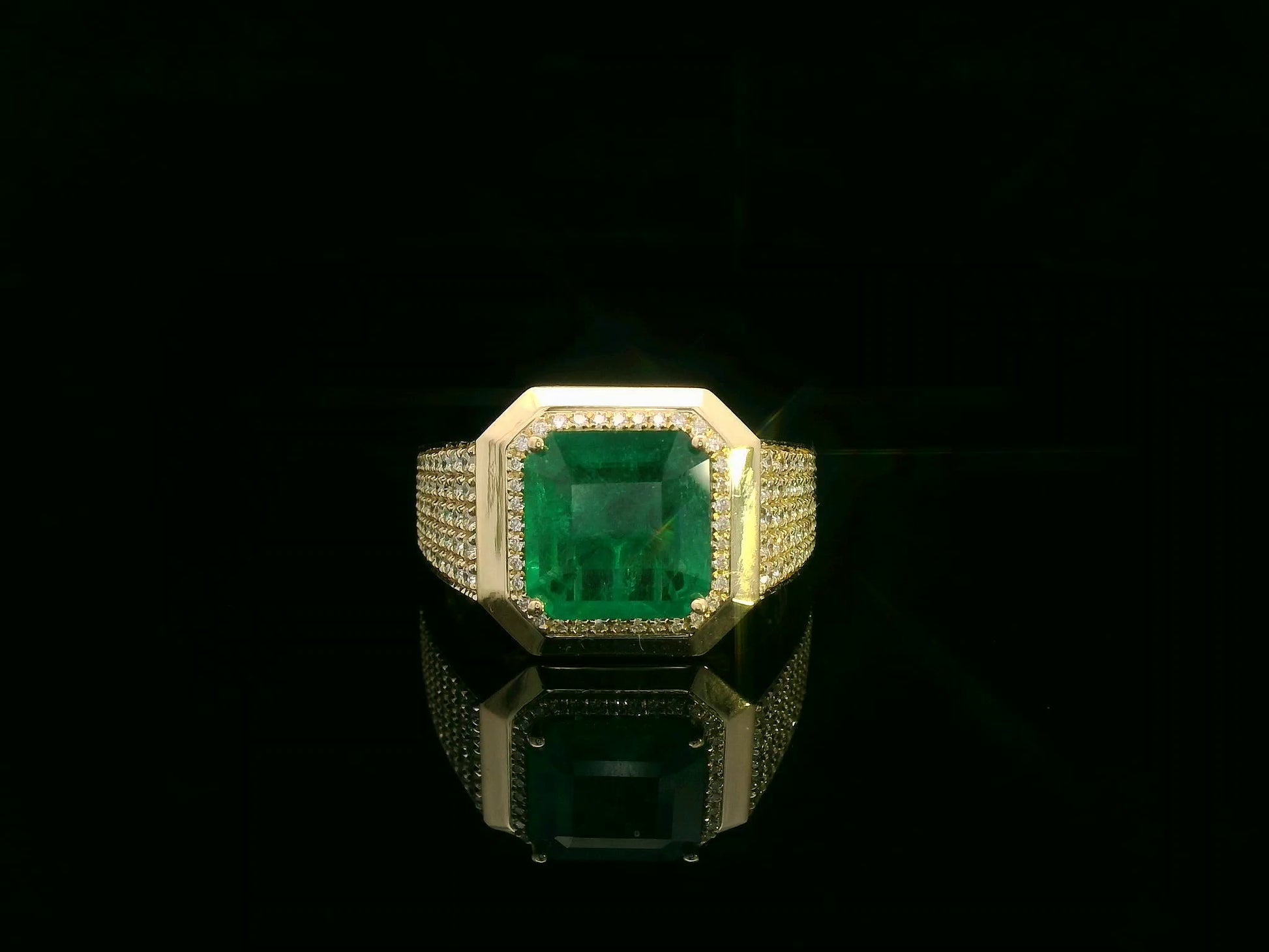 Men’s 18K yellow gold emerald and diamond statement ring featuring a 3.30 carat emerald with diamond halo and wide pavé band by Emirates Diamonds