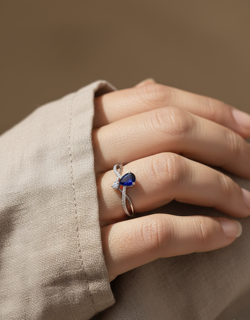 18K white gold blue sapphire and diamond crossover band ring, pear-shaped sapphire with pavé diamond accents by Emirates Diamonds