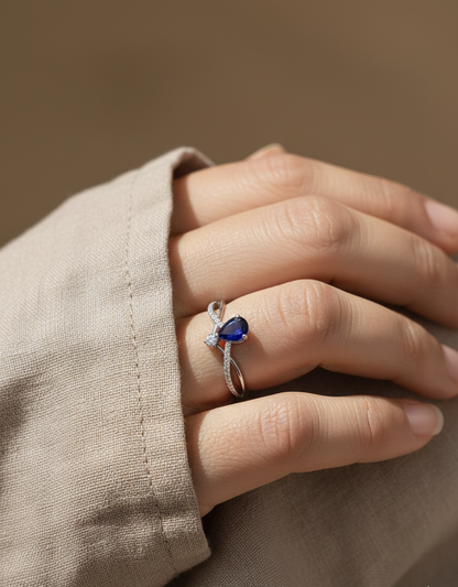 18K white gold blue sapphire and diamond crossover band ring, pear-shaped sapphire with pavé diamond accents by Emirates Diamonds