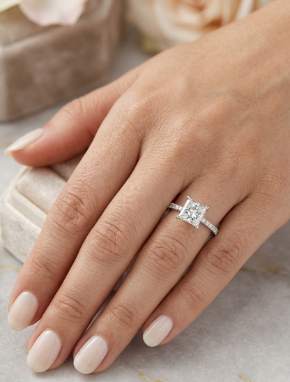 18K white gold engagement ring featuring a 1.50 carat IGI certified natural princess cut diamond with G color and SI2 clarity, accented by 0.20 carat natural round brilliant diamonds on the band.