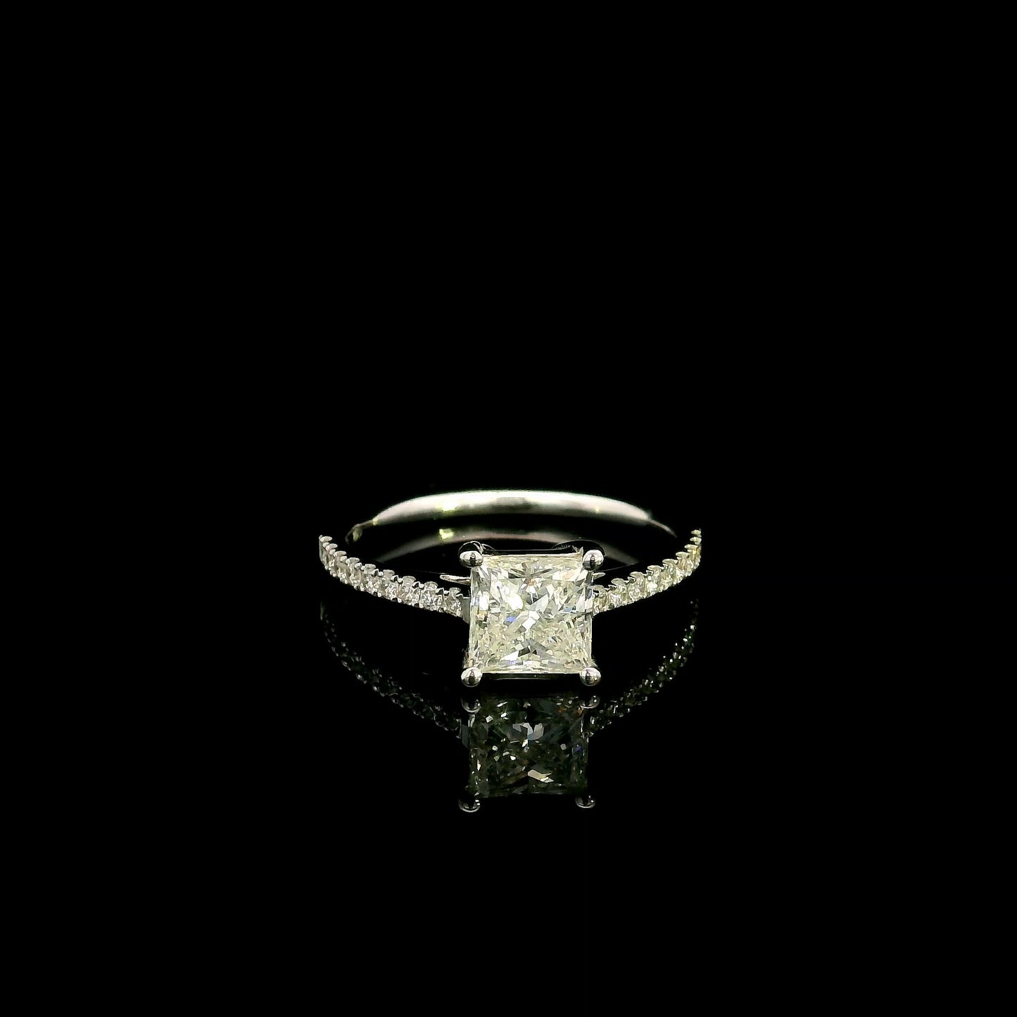 18K white gold engagement ring featuring a 1.50 carat IGI certified natural princess cut diamond with G color and SI2 clarity, accented by 0.20 carat natural round brilliant diamonds on the band.