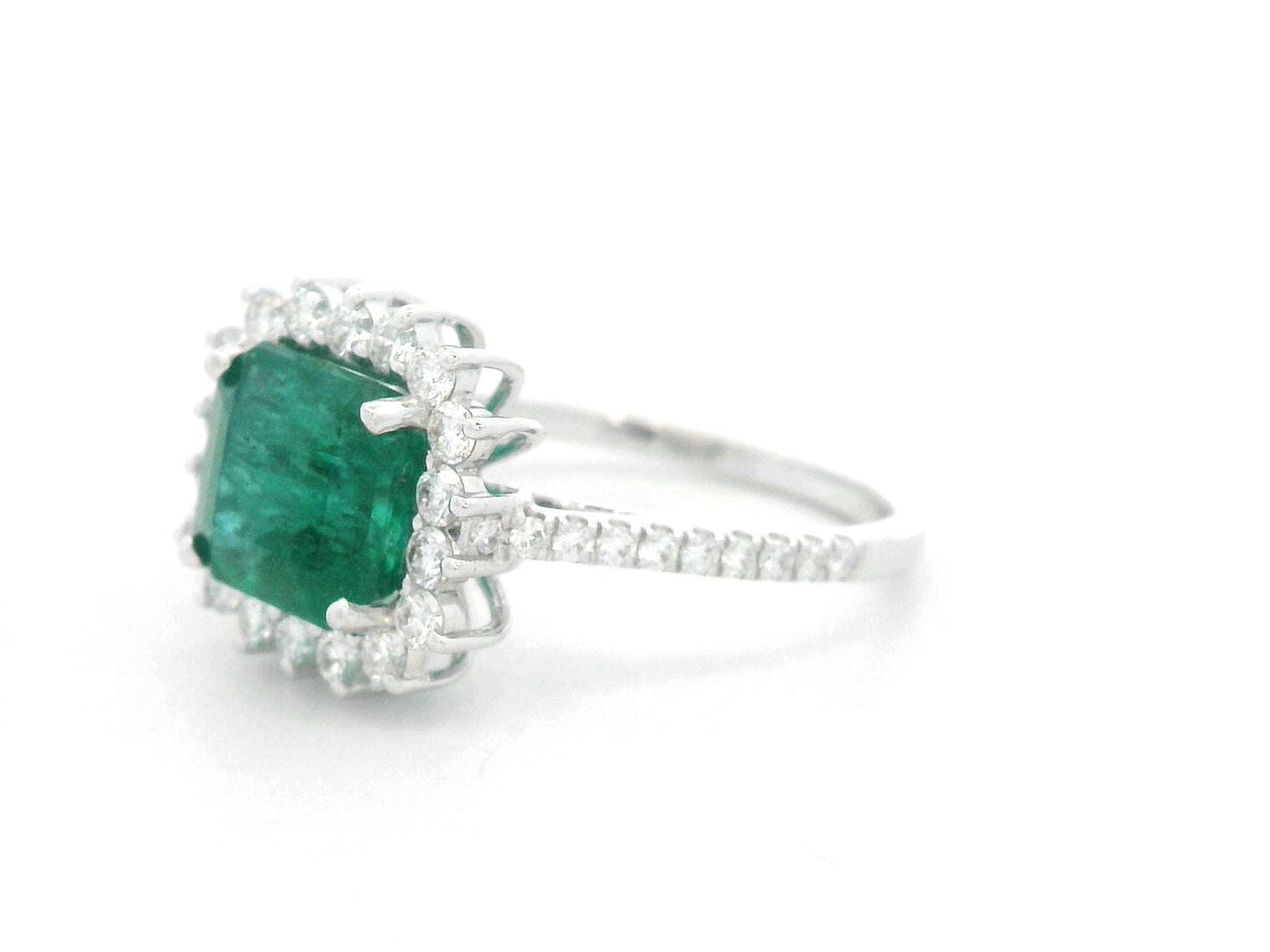 Emerald and diamond halo ring in 18K white gold featuring a 2.12 carat emerald and pavé diamond band by Emirates Diamonds