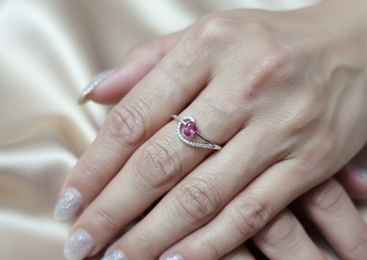 18K white gold ruby and diamond curved ring with oval ruby and flowing diamond-accented band by Emirates Diamonds
