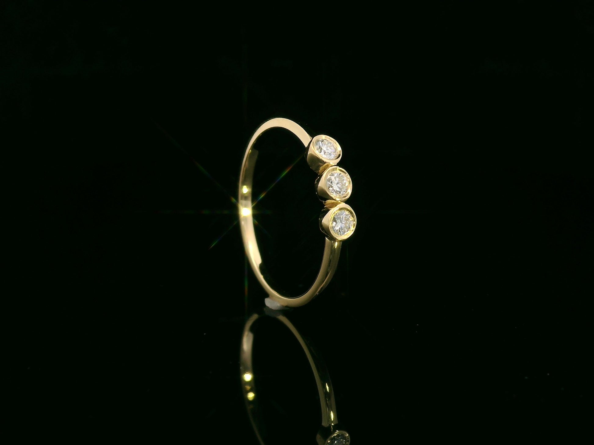 18K yellow gold three-stone natural diamond ring with minimalist bezel setting by Emirates Diamonds