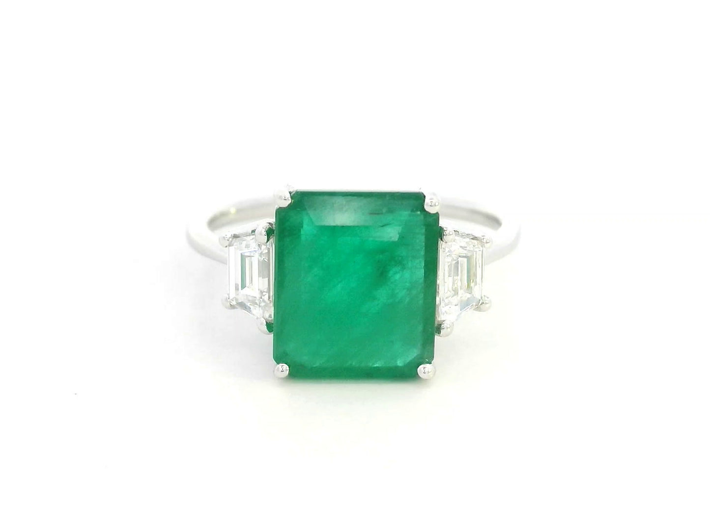 Emerald-cut emerald ring with trapezoid diamond side stones in 18K white gold by Emirates Diamonds.