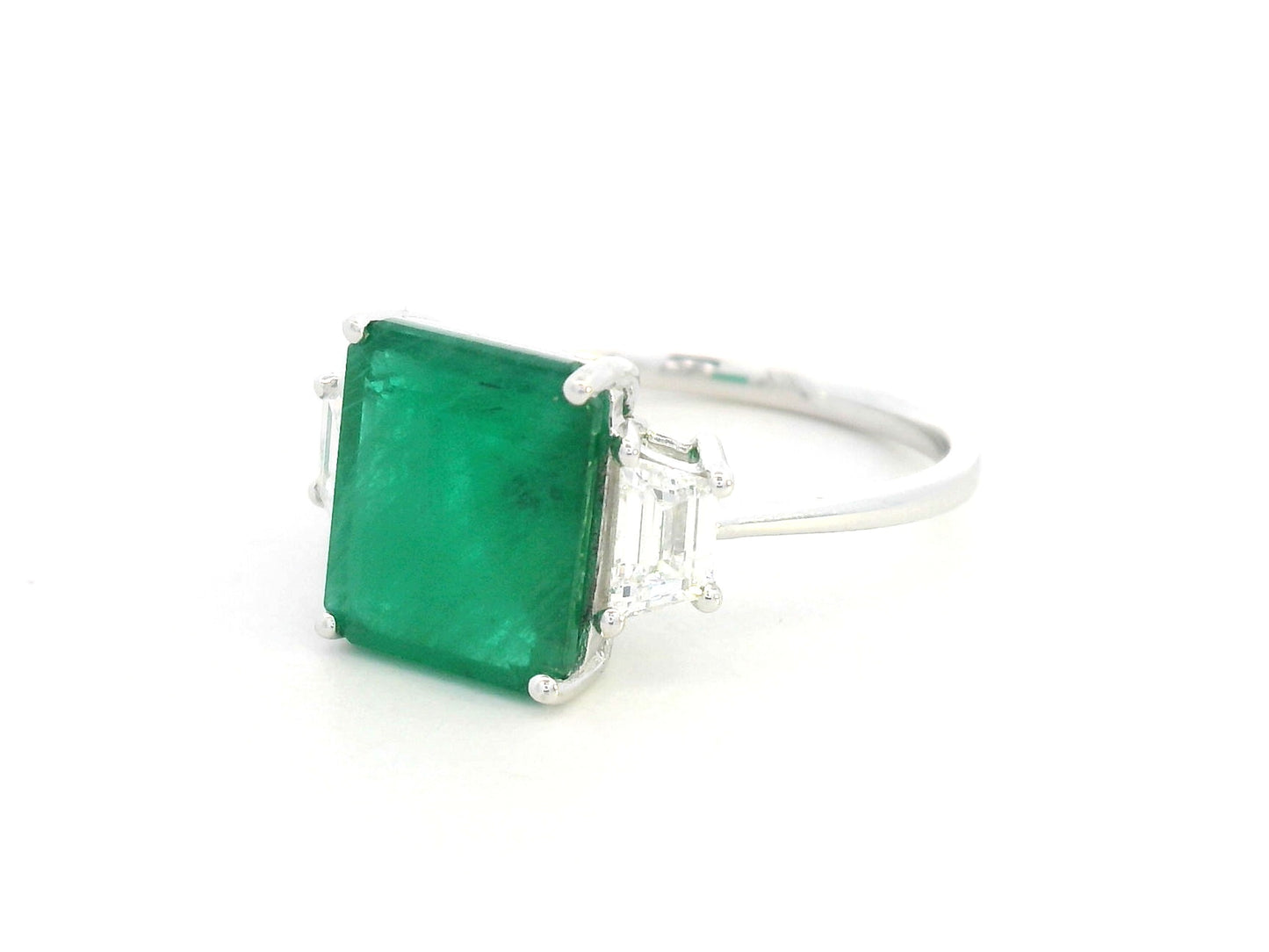 Emerald-cut emerald ring with trapezoid diamond side stones in 18K white gold by Emirates Diamonds.