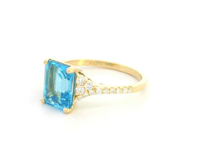 Emerald-cut blue topaz and diamond ring in 18K yellow gold by Emirates Diamonds.