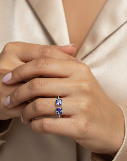 18K white gold open ring featuring two square emerald-cut tanzanites totaling 1.72 carats with 0.13 carat diamond accents by Emirates Diamonds.