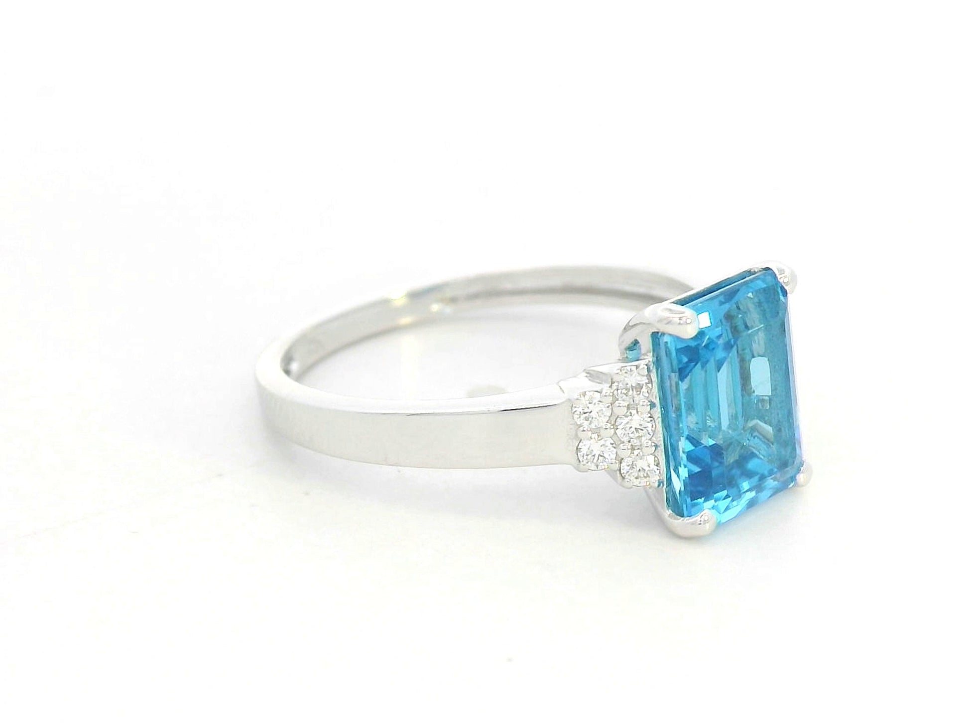 18K white gold emerald-cut Swiss blue topaz ring with diamond side accents by Emirates Diamonds