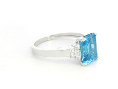 18K white gold emerald-cut Swiss blue topaz ring with diamond side accents by Emirates Diamonds