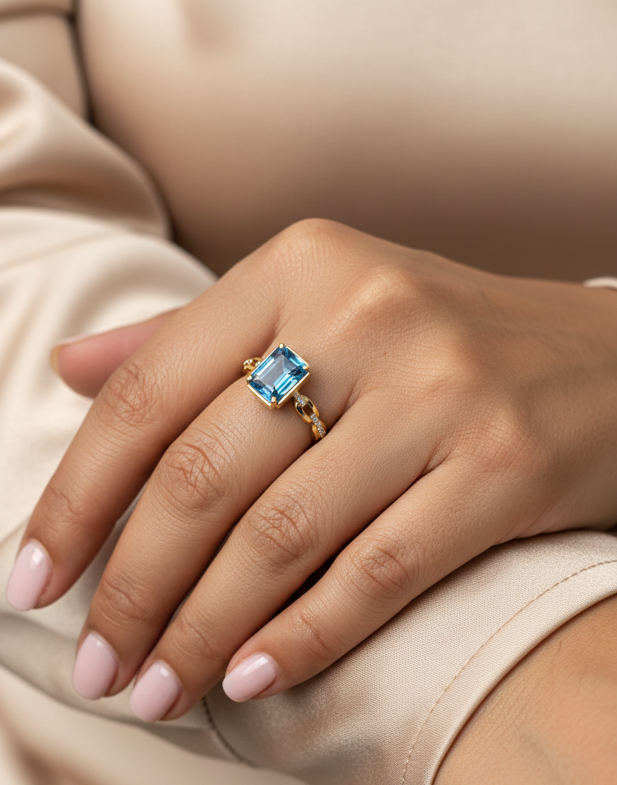 Emerald-cut Swiss blue topaz and diamond ring in 18K yellow gold by Emirates Diamonds.