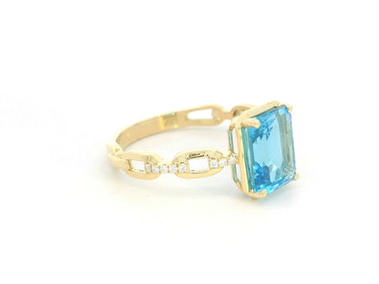 Emerald-cut Swiss blue topaz and diamond ring in 18K yellow gold by Emirates Diamonds.