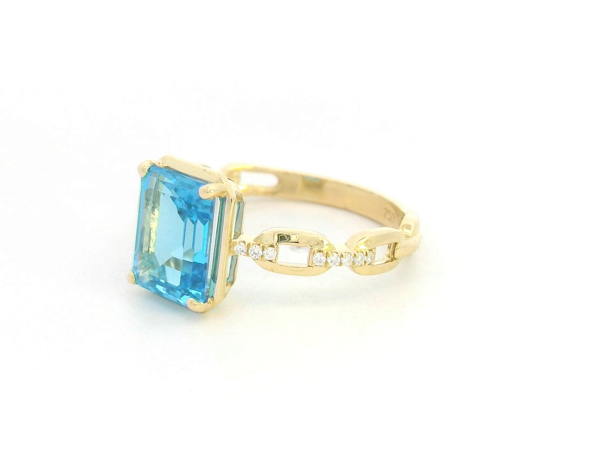Emerald-cut Swiss blue topaz and diamond ring in 18K yellow gold by Emirates Diamonds.