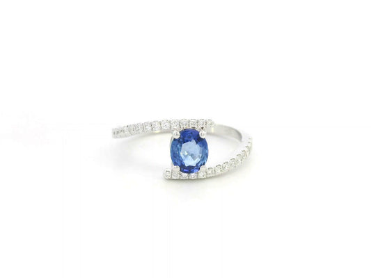 18K white gold open ring featuring a 0.76 carat oval blue sapphire with diamond accents, modern bypass design by Emirates Diamonds.