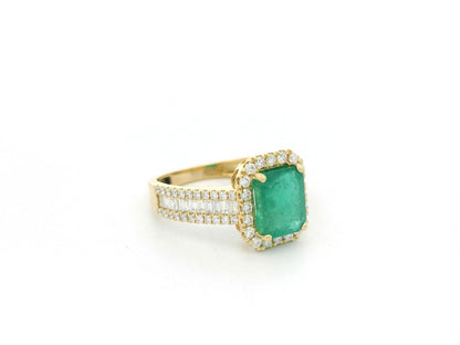 18K yellow gold emerald and diamond halo ring with baguette diamond accents by Emirates Diamonds.
