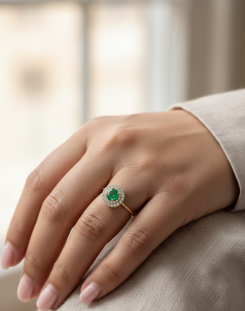 18K yellow gold emerald and diamond halo ring with round emerald center, luxury fine jewelry by Emirates Diamonds.