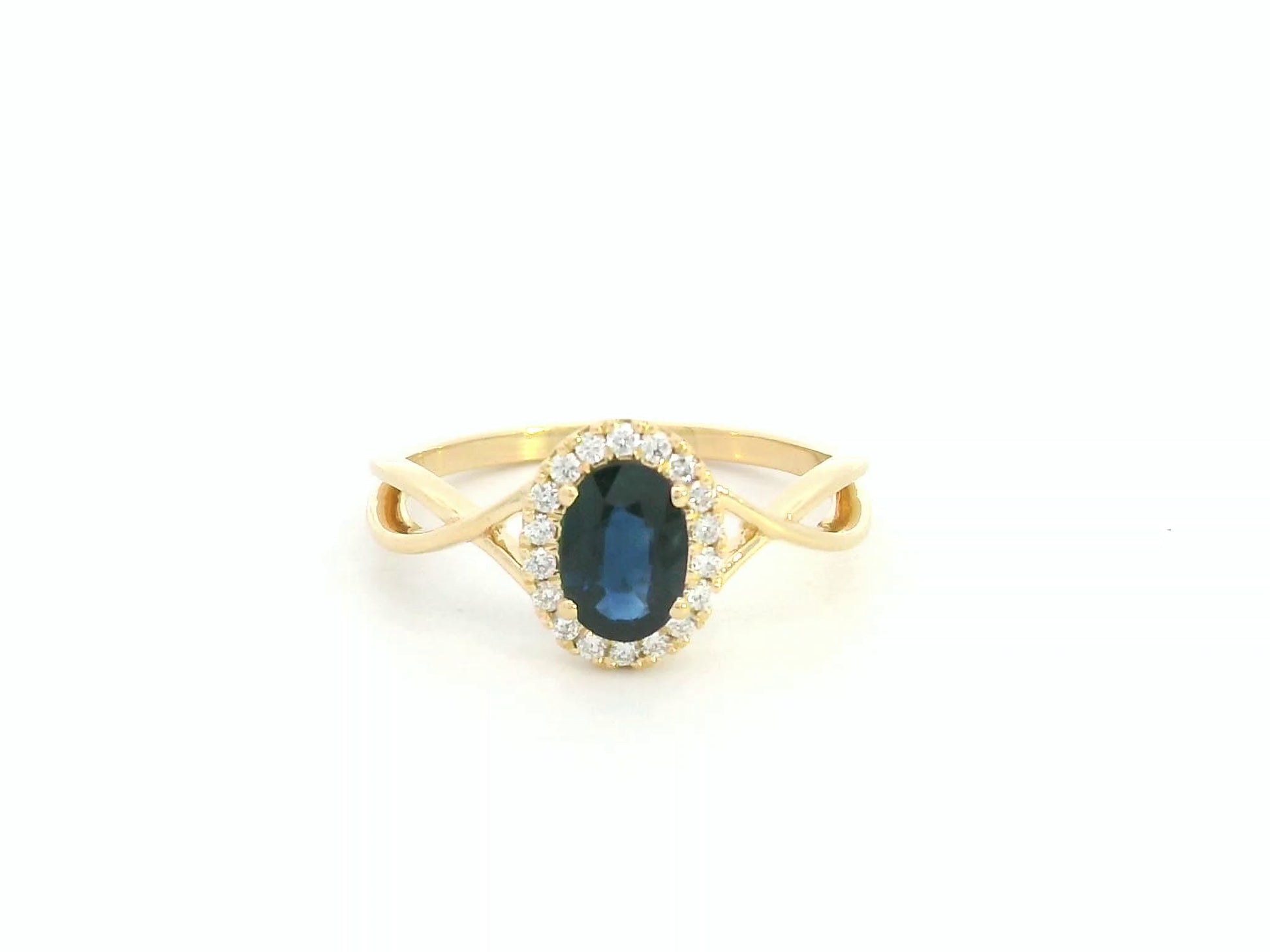 Oval blue sapphire diamond halo ring in 18K yellow gold with crossover band by Emirates Diamonds