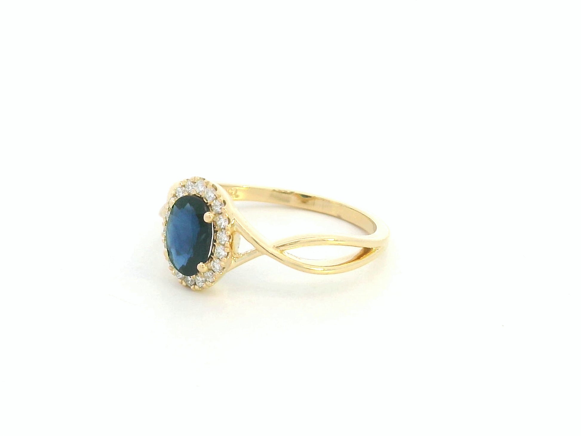 Oval blue sapphire diamond halo ring in 18K yellow gold with crossover band by Emirates Diamonds